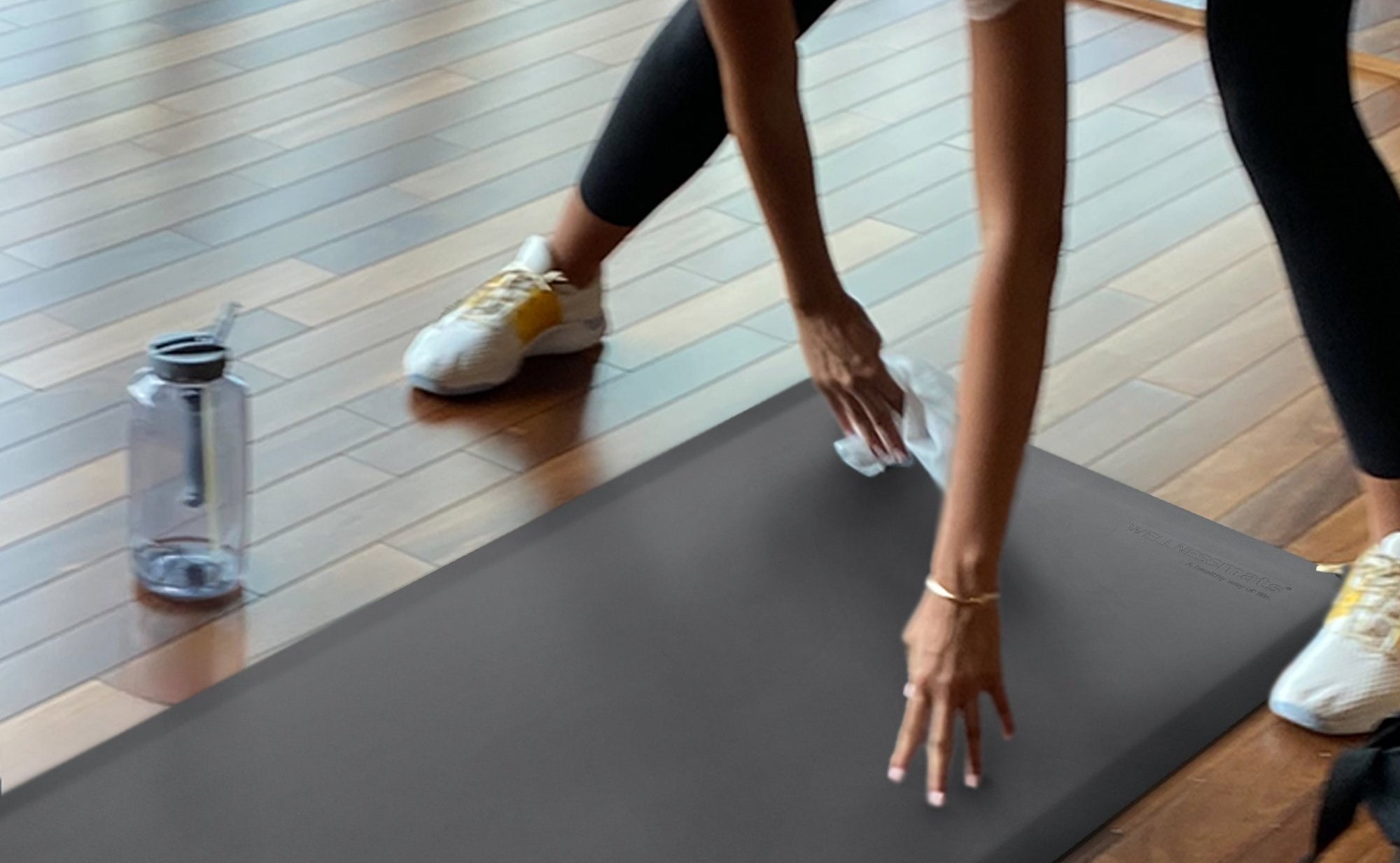 A woman wiping down a FitnessMat in the a home gym.
