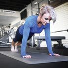 A woman at a gym doing push-ups on a gray FitnessMat