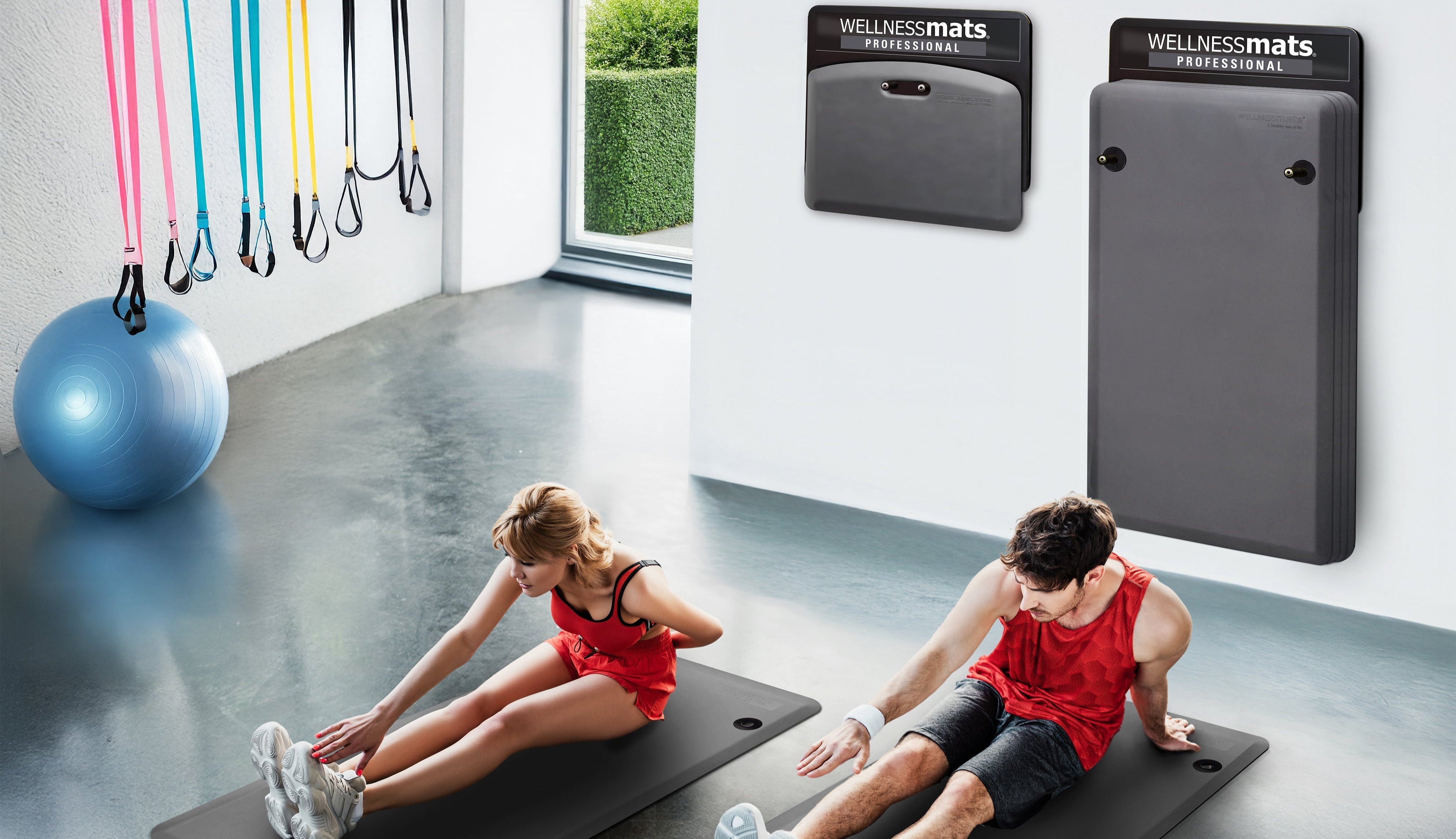 Couple stretching in gym on gray FitnessMats