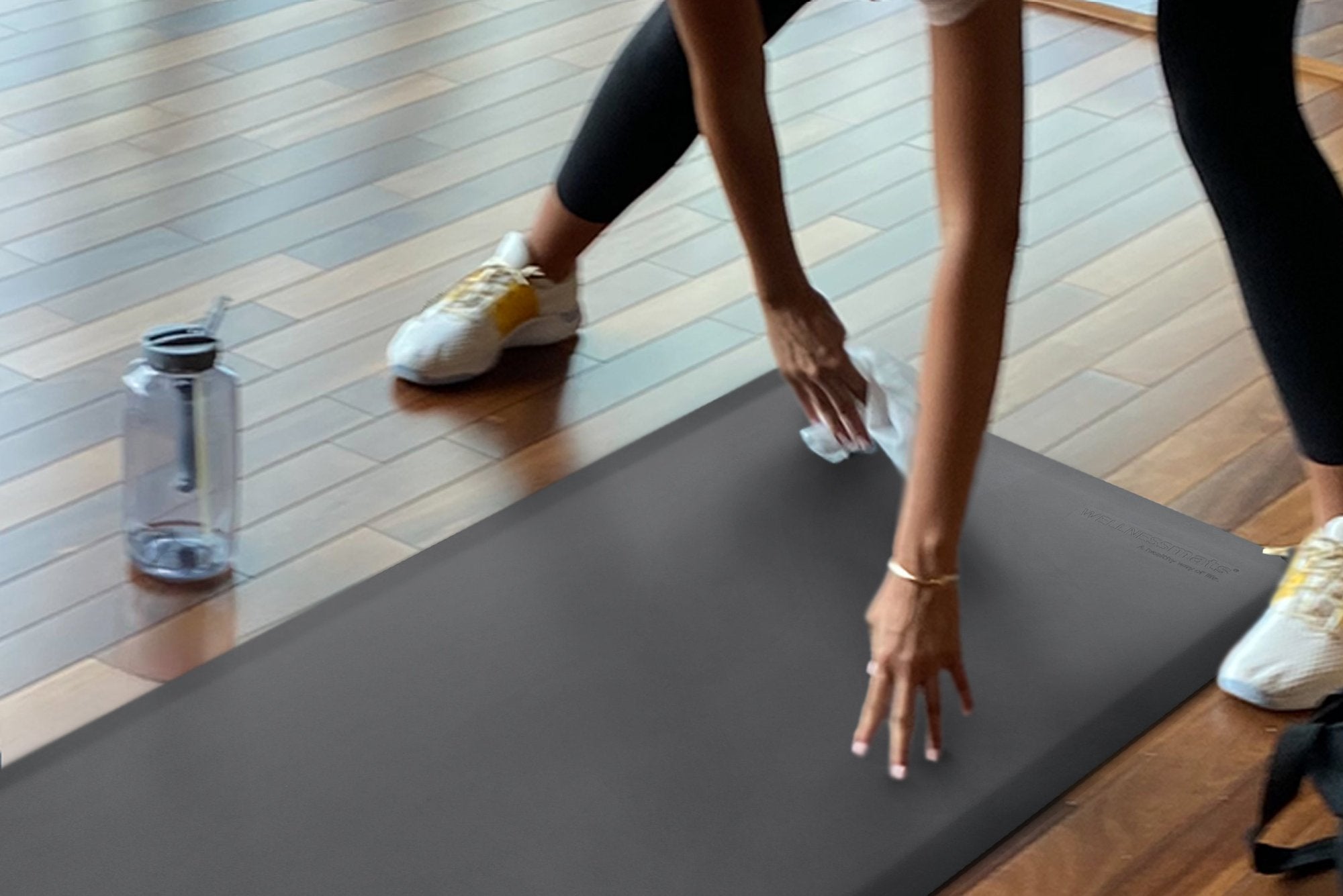 A woman wiping down a FitnessMat in the a home gym. 